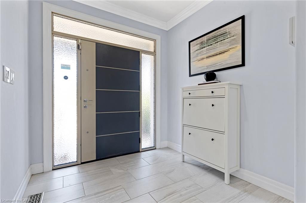 Entryway featuring a modern door with frosted glass sidelights and transom window, light-toned tile flooring, and crisp white baseboards and crown molding