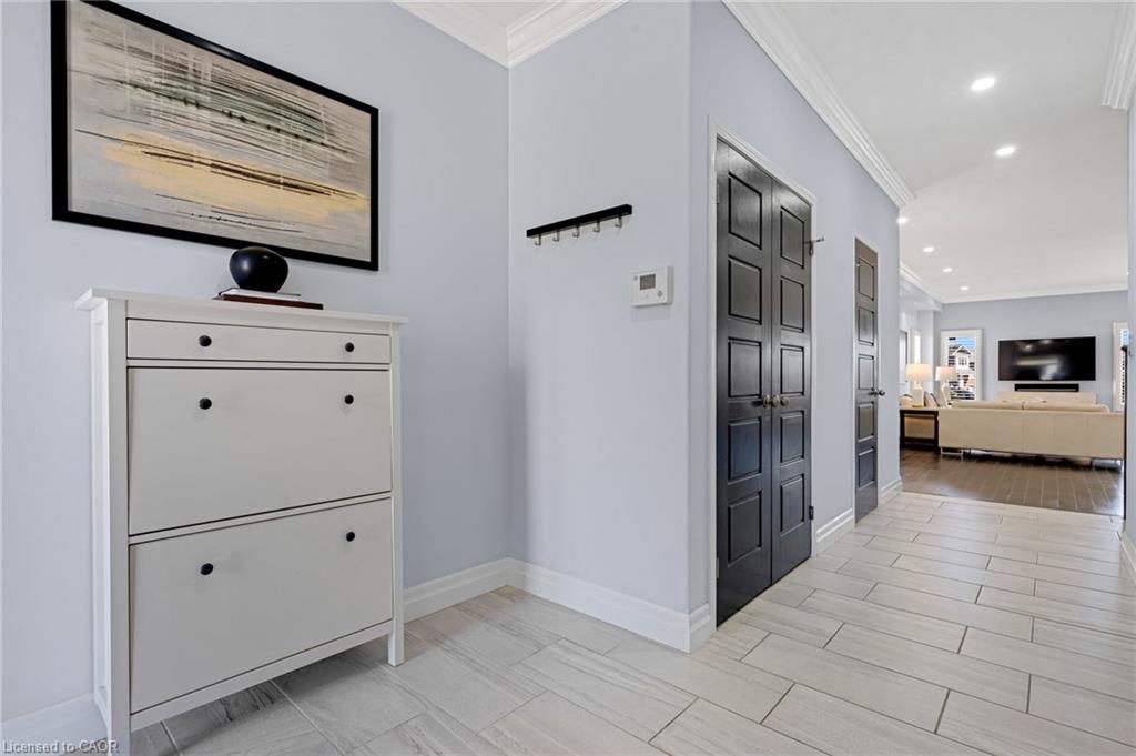 Welcoming foyer featuring light-filled tile flooring, soft gray walls, and a white shoe cabinet with black hardware and integrated pull-out storage