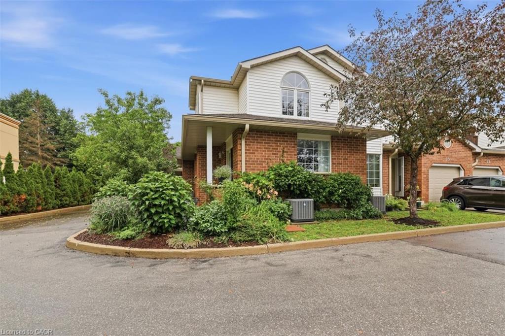 Brick and siding exterior featuring an arched window, covered entryway, mature landscaping, and an asphalt driveway