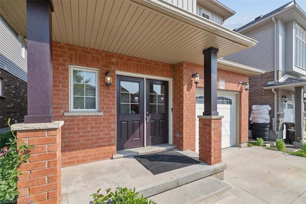 Brick exterior with covered front entry, double entry doors, exterior lighting, and an attached garage with an arched panel door