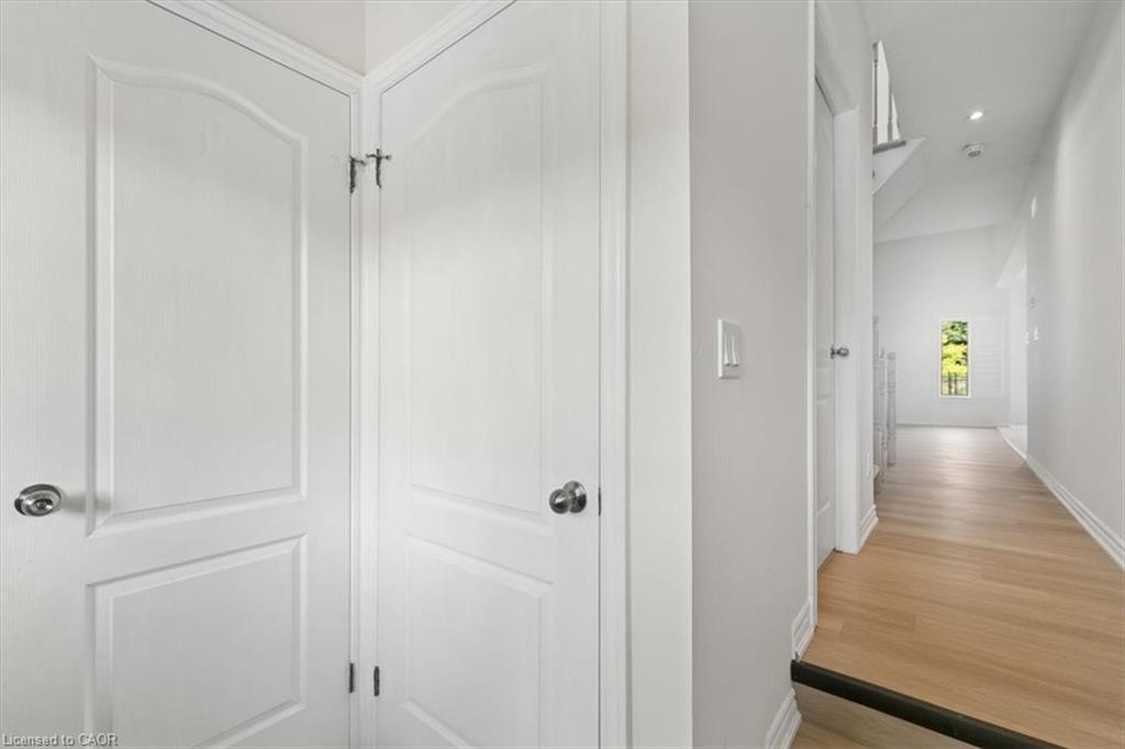 Light wood-finish flooring, white walls, white doors with paneling, and recessed lighting