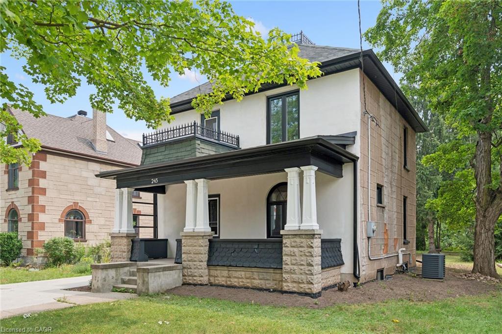 Stucco and stone exterior with a covered porch featuring decorative pillars and a second-story balcony with wrought iron railing