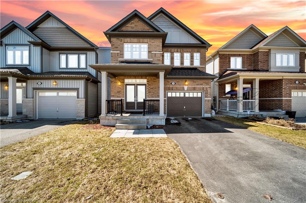 Two-story brick and siding construction featuring a covered front porch, a paver stone walkway, and a paved driveway leading to an integrated garage