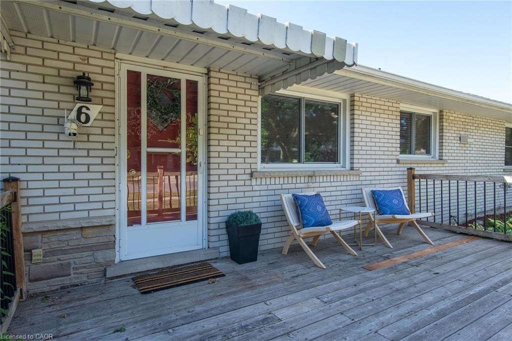 Front entrance featuring a white storm door, light brick exterior, and a wood-finish porch