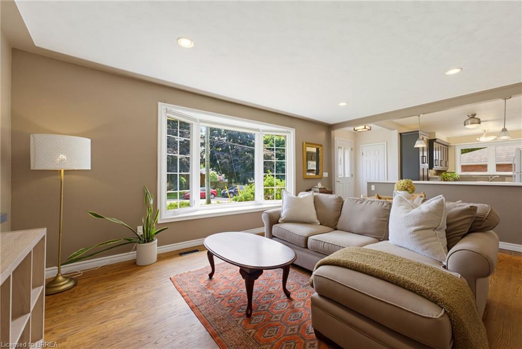 Recessed lighting, wood-finish flooring, bay window, open concept layout, and kitchen pass-through with pendant lighting