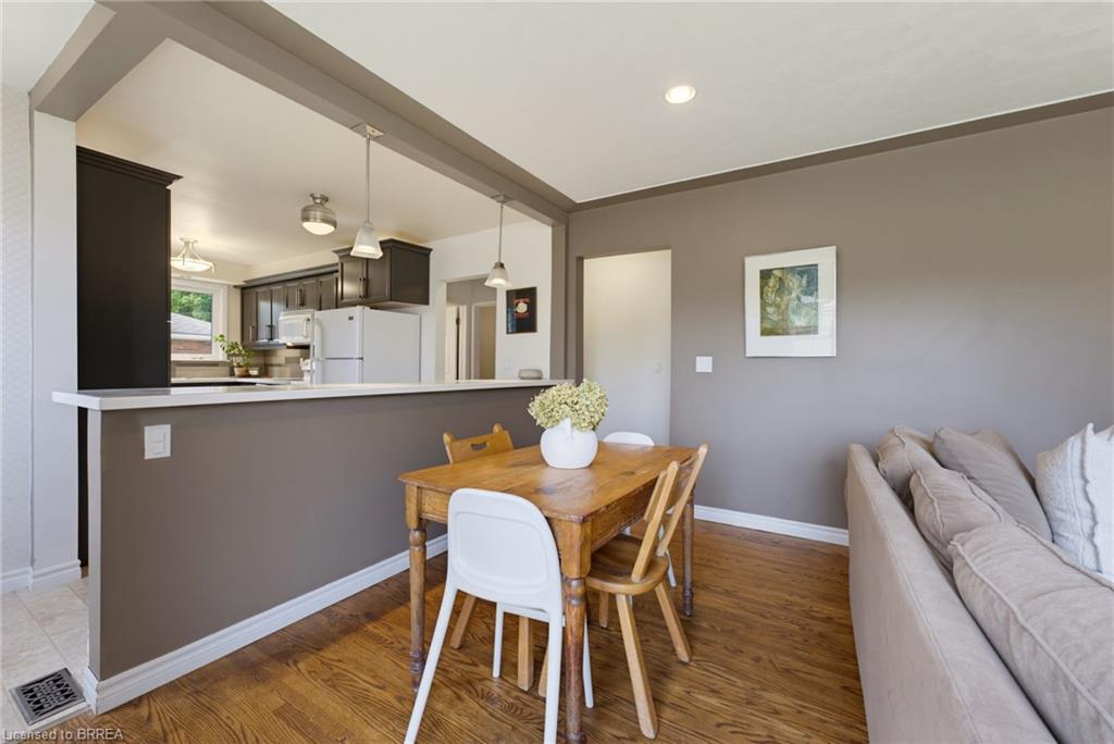 Kitchen with dark cabinetry and white appliances, featuring a peninsula with countertop seating