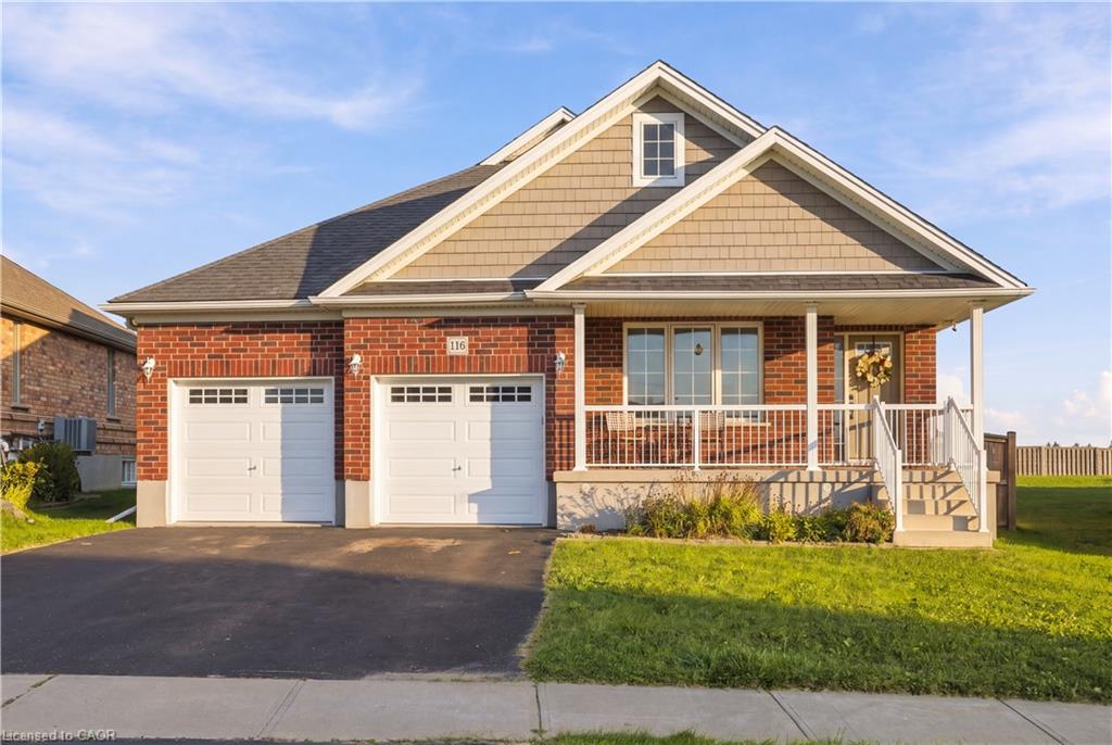 Brick and shingle exterior with a covered porch, two-car garage, and a peaked roofline