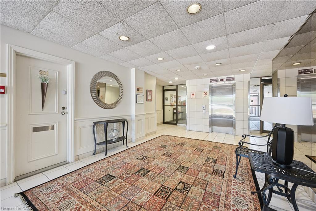Welcoming entrance foyer featuring recessed ceiling lighting, decorative round mirror accent, neutral drop-ceiling with integrated fixtures, and patterned tile flooring
