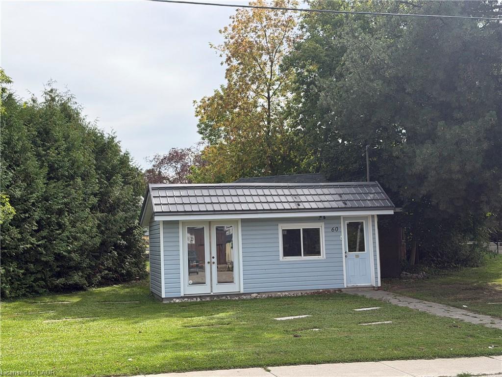 Light blue horizontal siding, dark shingled roof, white trim, double glass doors, and a single window