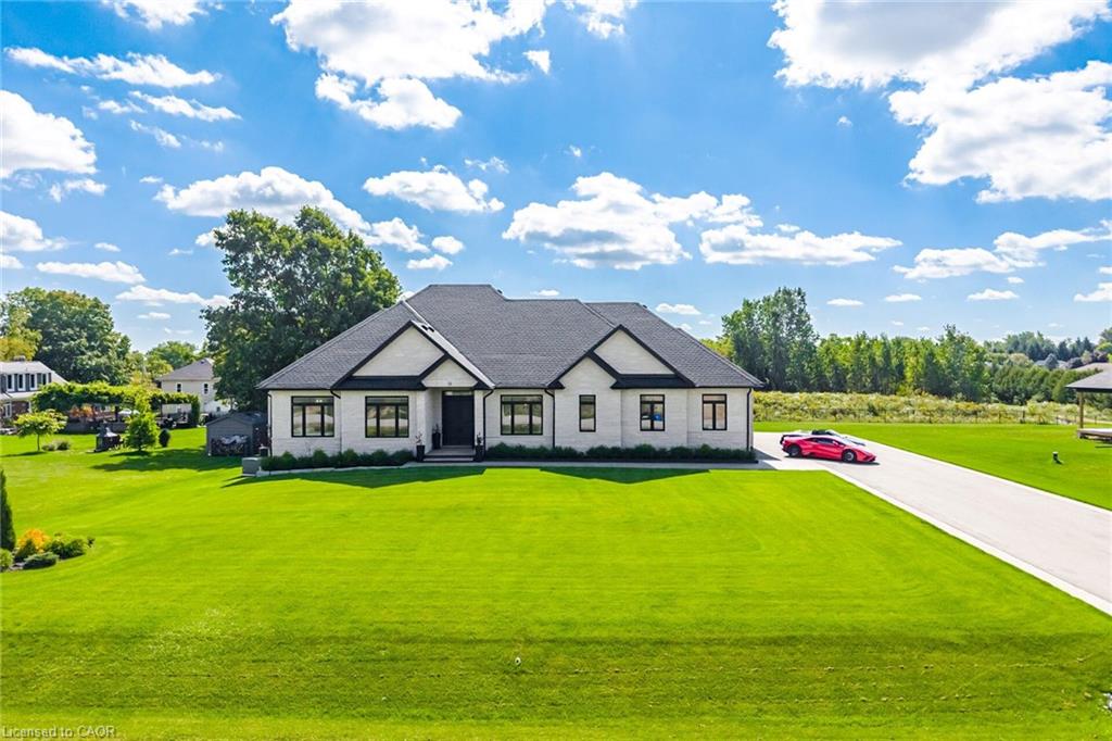 White exterior with black-framed windows, dark roof, and a paved driveway