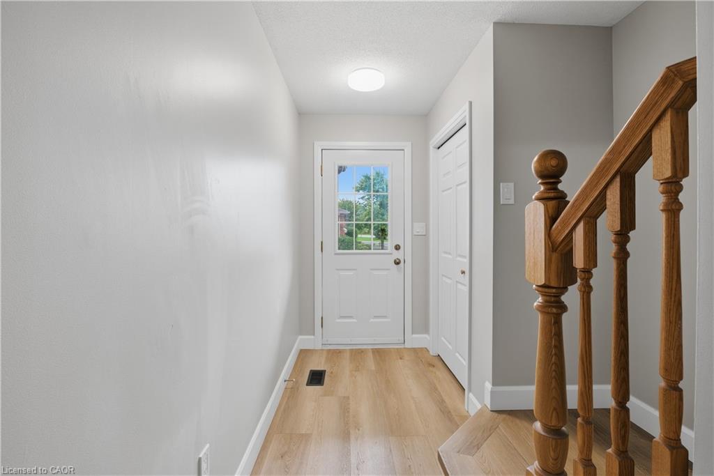 Entryway featuring wood-finish flooring, a white paneled door with windowpanes, a recessed ceiling light, and a built-in closet