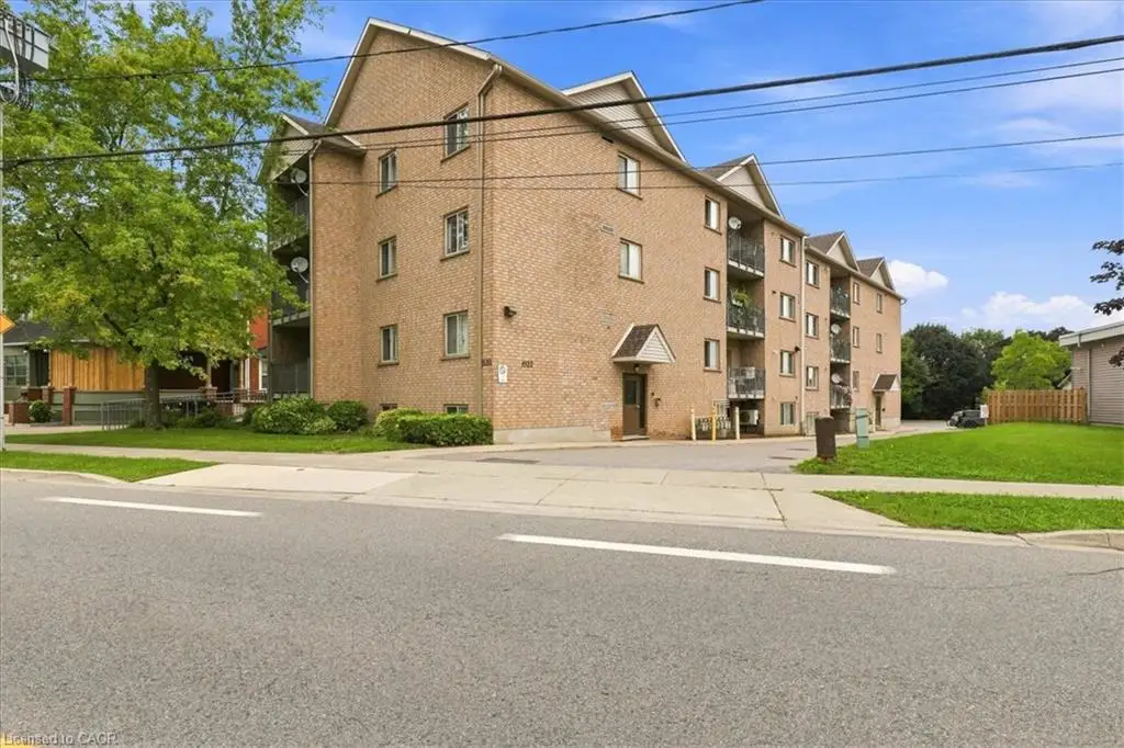 Brick exterior building with multiple levels, individual balconies, and a paved parking area