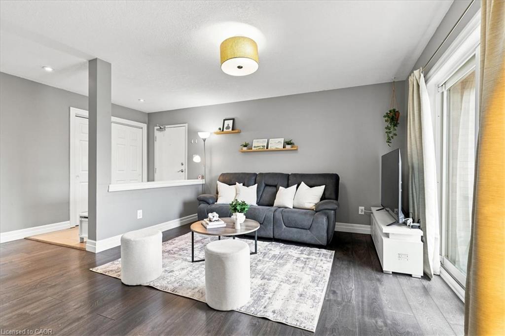 Spacious living area featuring wood-finish flooring, light gray walls, a sliding glass door, and a semi-recessed ceiling light fixture