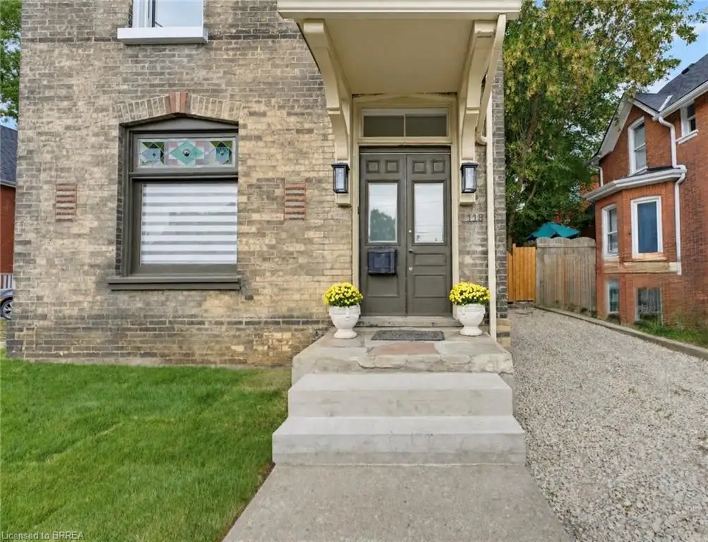 Brick exterior with architectural detailing, covered front entry, twin entry doors, exterior sconces, and gravel driveway