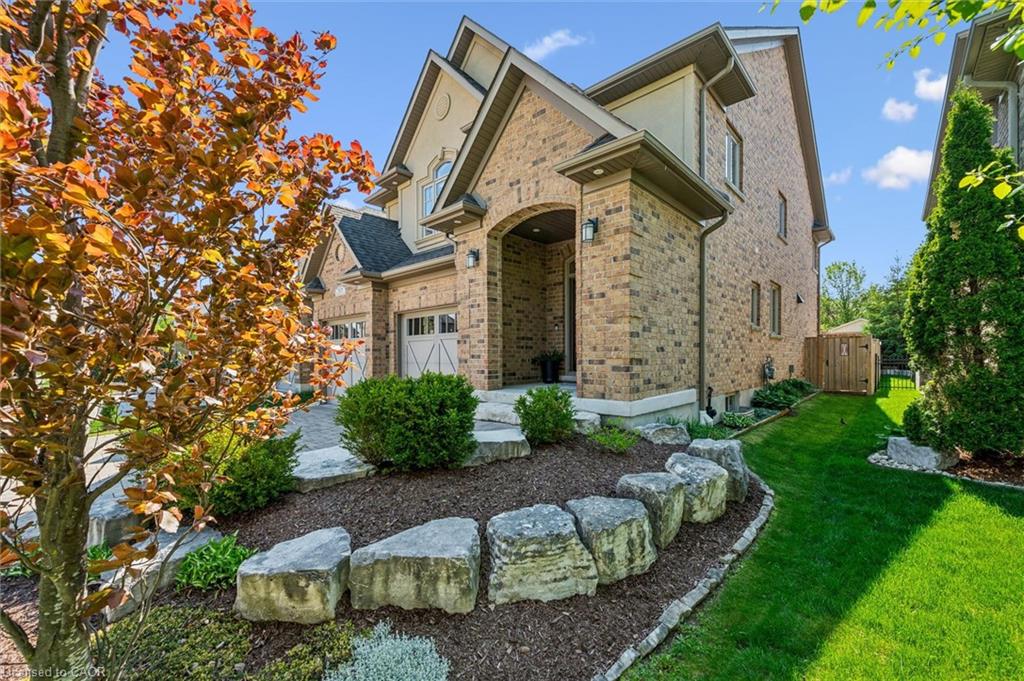 Brick facade residence featuring an arched entryway, gabled rooflines, and a two-car garage.