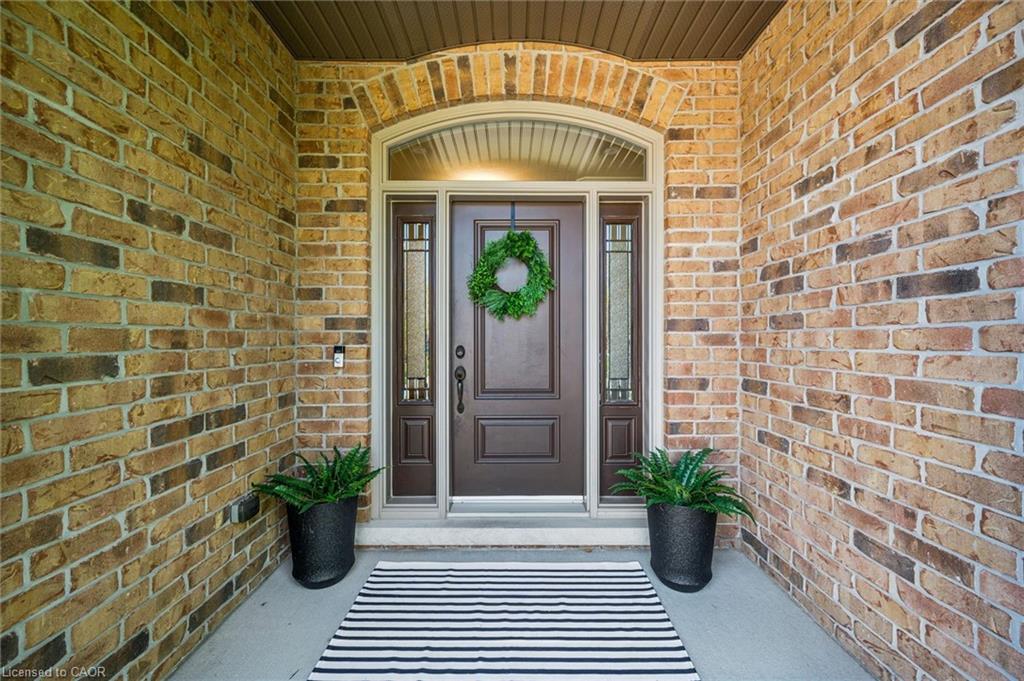 Arched entry featuring brick exterior, a dark wood-finish door, and sidelight windows with decorative glass.