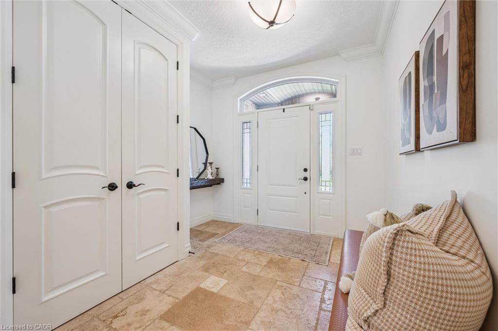 Entryway featuring stone tile flooring, white arched panel doors, crown molding, a transom window, and sidelight windows.