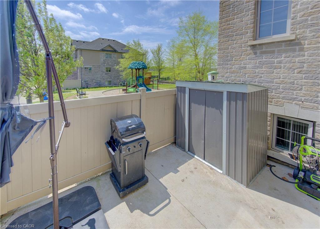 Private concrete patio area featuring a corrugated metal storage shed and a privacy fence