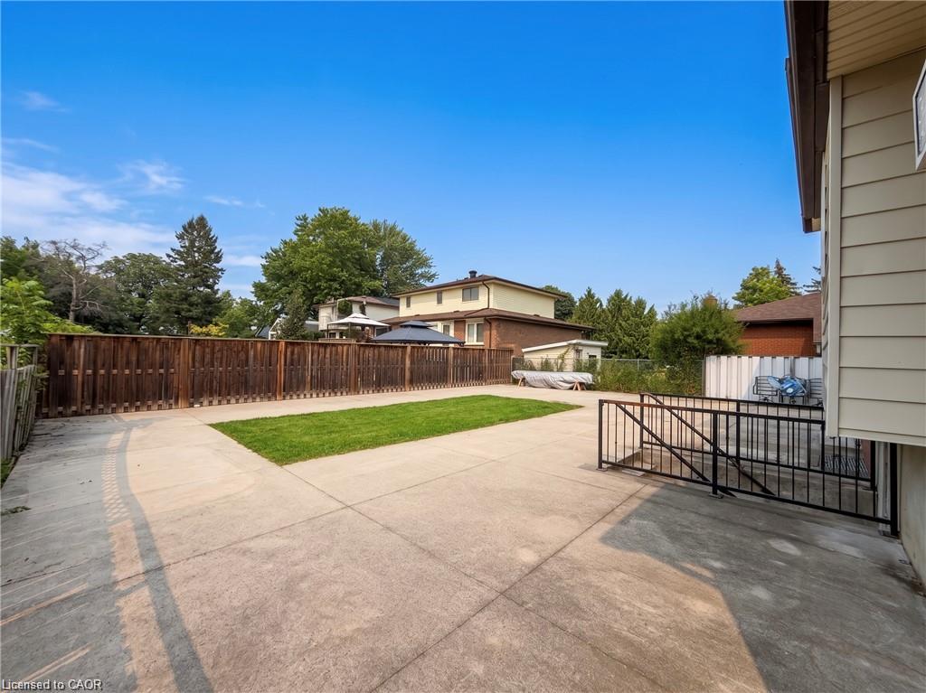 Expansive concrete patio with a central grass area, surrounded by a wood privacy fence