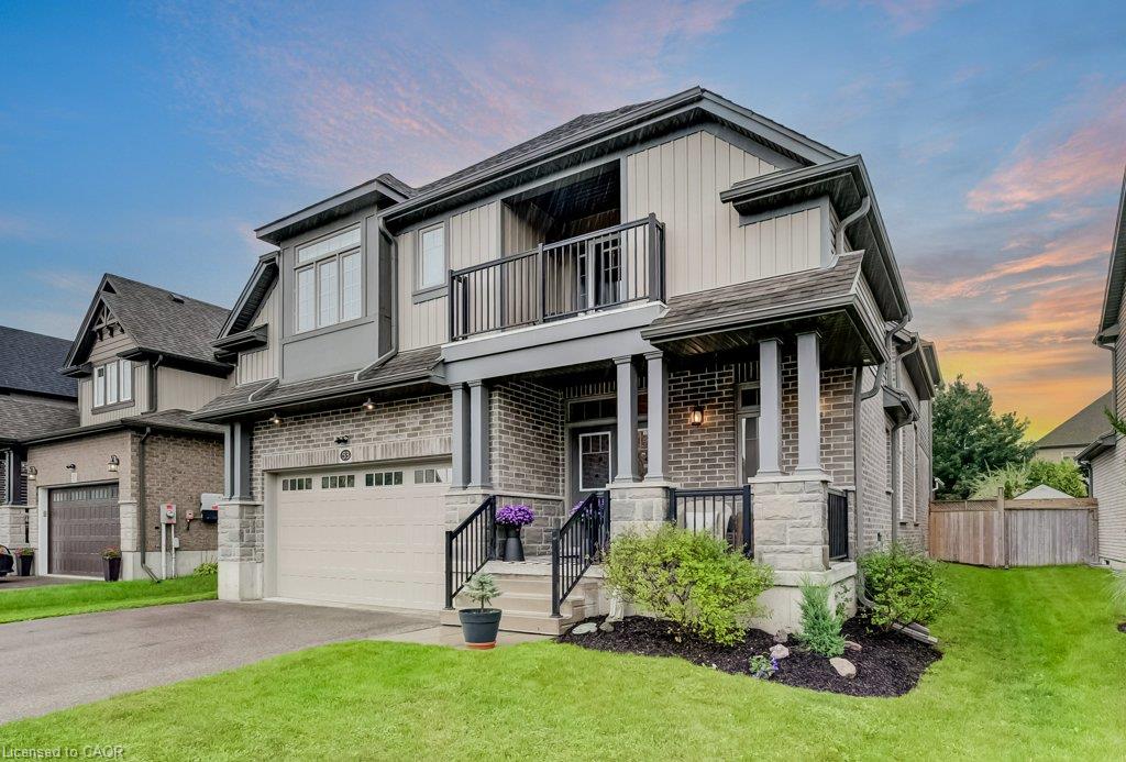 Brick and stone facade with vertical siding accents, covered front porch with columns, upper-level balcony, and an attached garage with a paved driveway