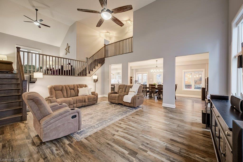 Vaulted ceilings with ceiling fans, wood-finish flooring, and a two-story staircase with wood railing