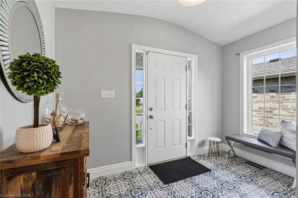 Patterned floor tile, white paneled entry door, sidelight windows, and a large window with white trim