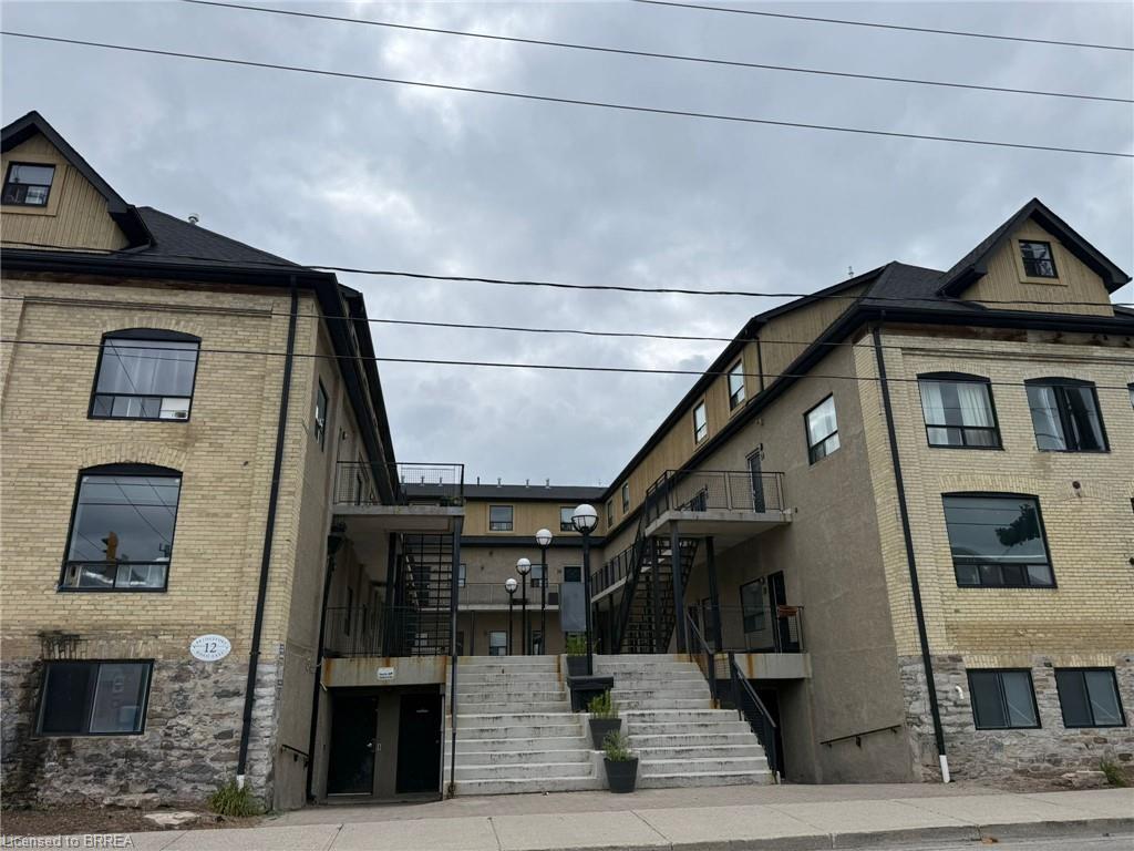 Brick and stone facade building with multiple windows, black roof, and exterior stairways