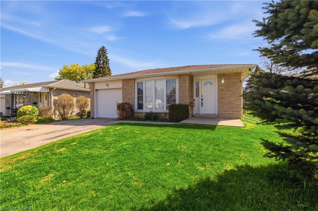 Front of home featuring attached garage, large driveway and landscaped front lawn/garden