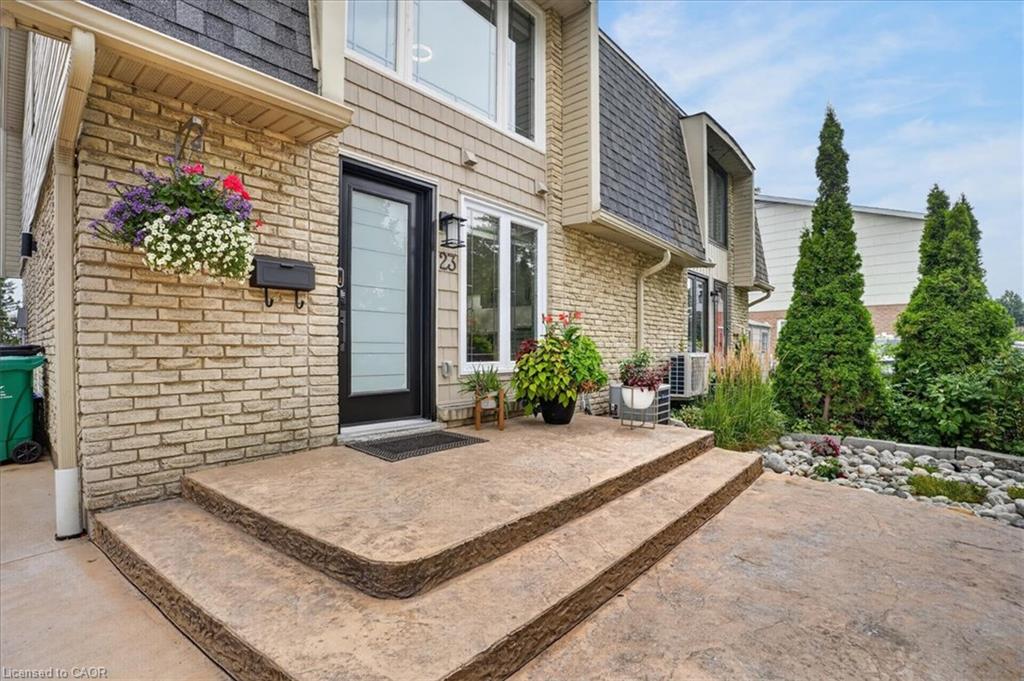 Brick and siding exterior featuring a black entry door with frosted glass panels, an exterior light fixture, and a stamped concrete walkway with steps