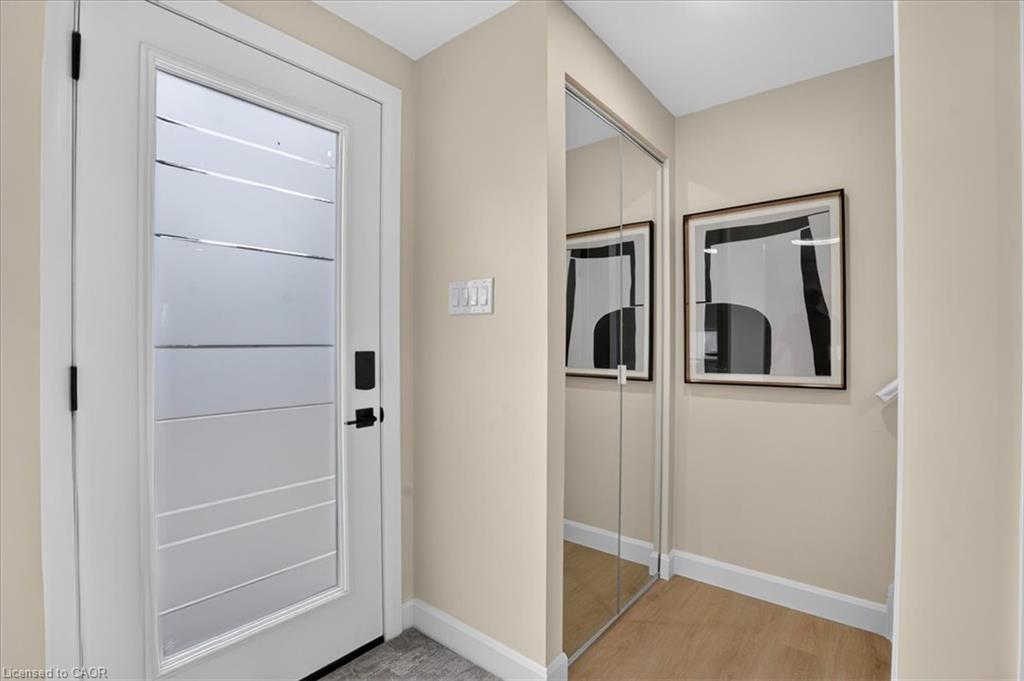 Entryway featuring a contemporary door with frosted glass panels, black hardware, mirrored closet doors, and wood-finish flooring