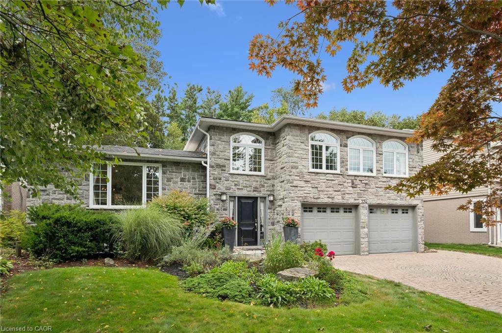 Stone exterior featuring multiple arched windows, a two-car garage, and a paver driveway