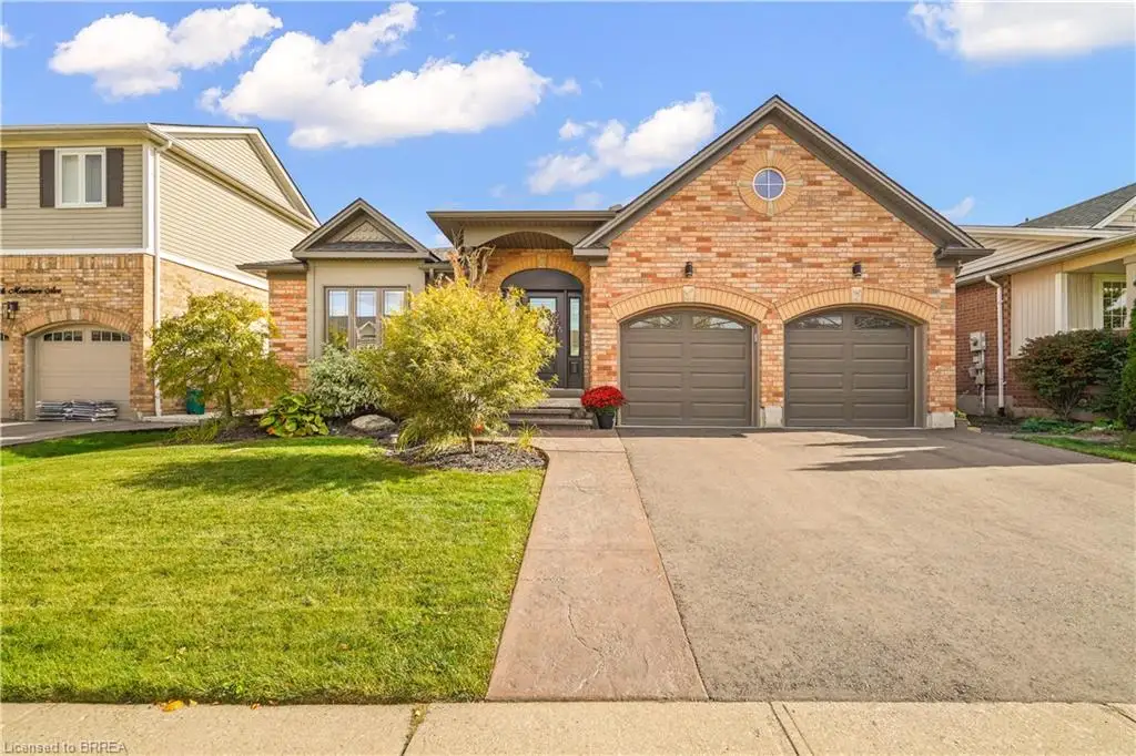 Brick exterior featuring double garage doors, arched masonry detailing, a circular gable window, and a paved driveway