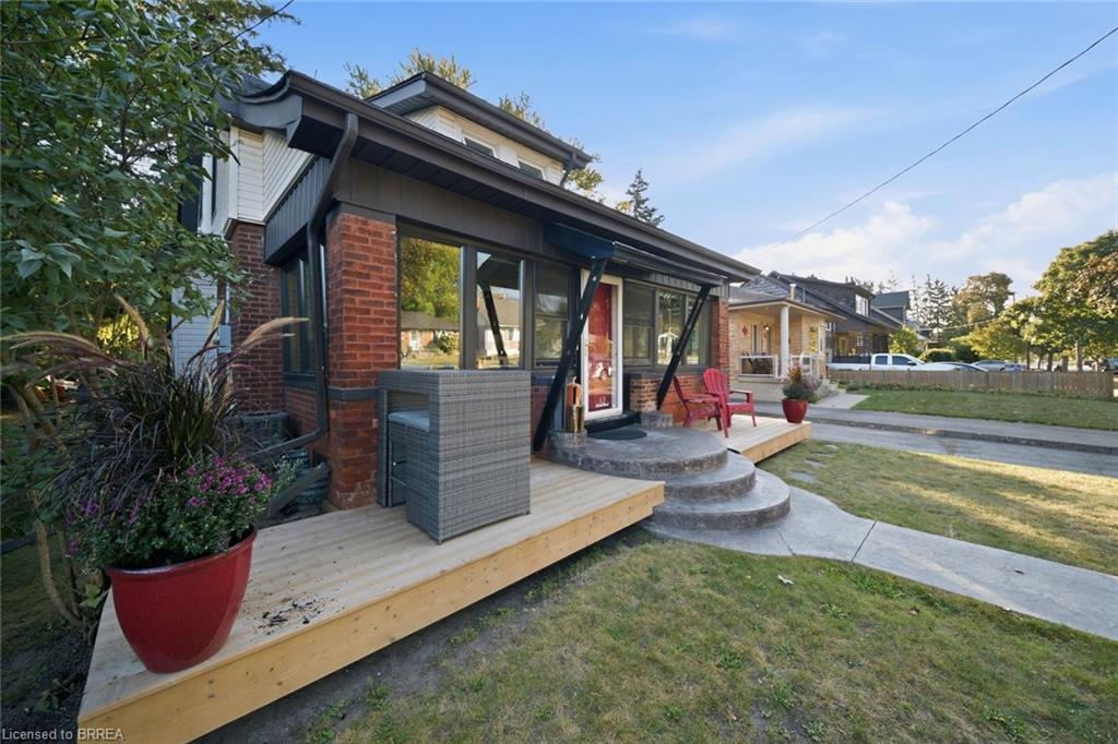 Brick exterior with dark trim accents, featuring a wood-finish deck and concrete steps
