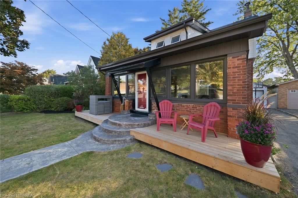 Brick exterior with a dormer, wood deck, and concrete pathway