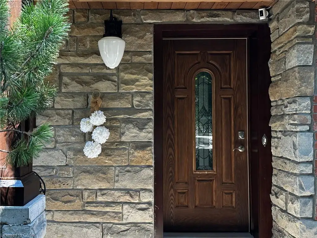 Elegant stone facade entry featuring a substantial dark wood door with decorative panel detailing and beveled glass insert