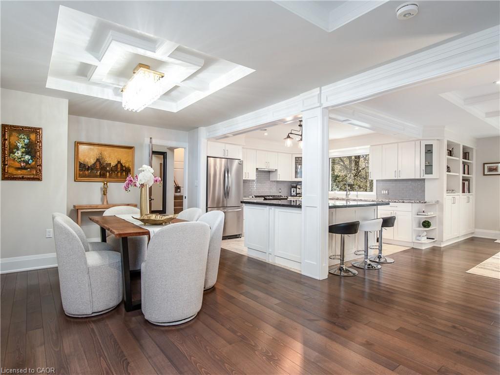Open-concept living and dining area featuring wood-finish flooring, recessed ceiling lighting with skylight panels, and a curved upholstered dining chair