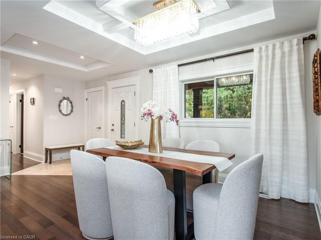 Dining area featuring wood-finish flooring, a tray ceiling with recessed lighting and a chandelier, and a large window