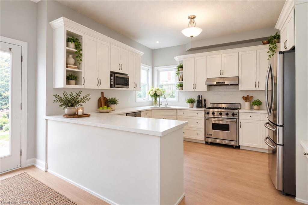 White shaker cabinetry, light wood-finish flooring, stainless steel appliances, white countertop, and subway tile backsplash