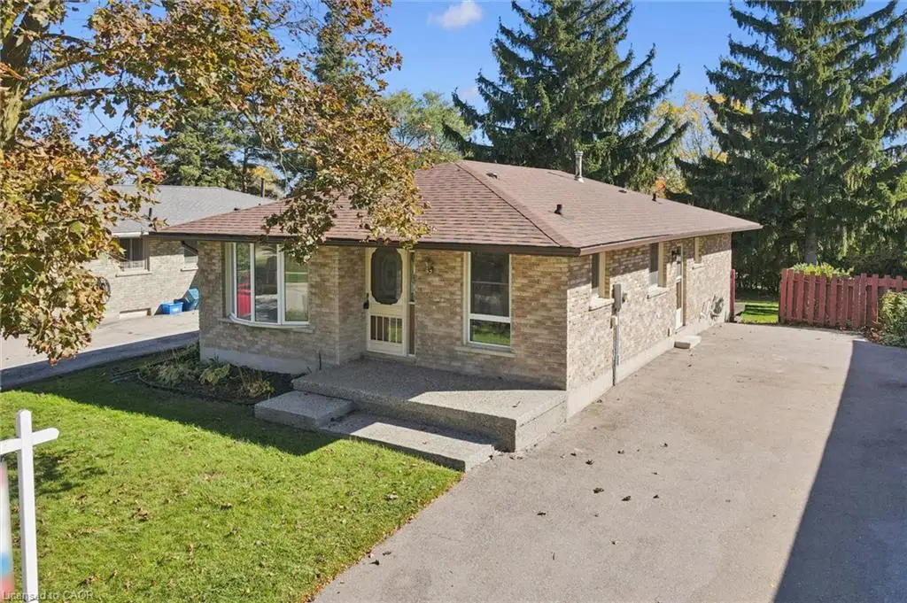 Single-story brick exterior with a low-slope roof, bay window, concrete front porch, and paved driveway