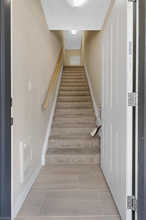 Tiled entry flooring, carpeted staircase, light wood handrail, and recessed lighting
