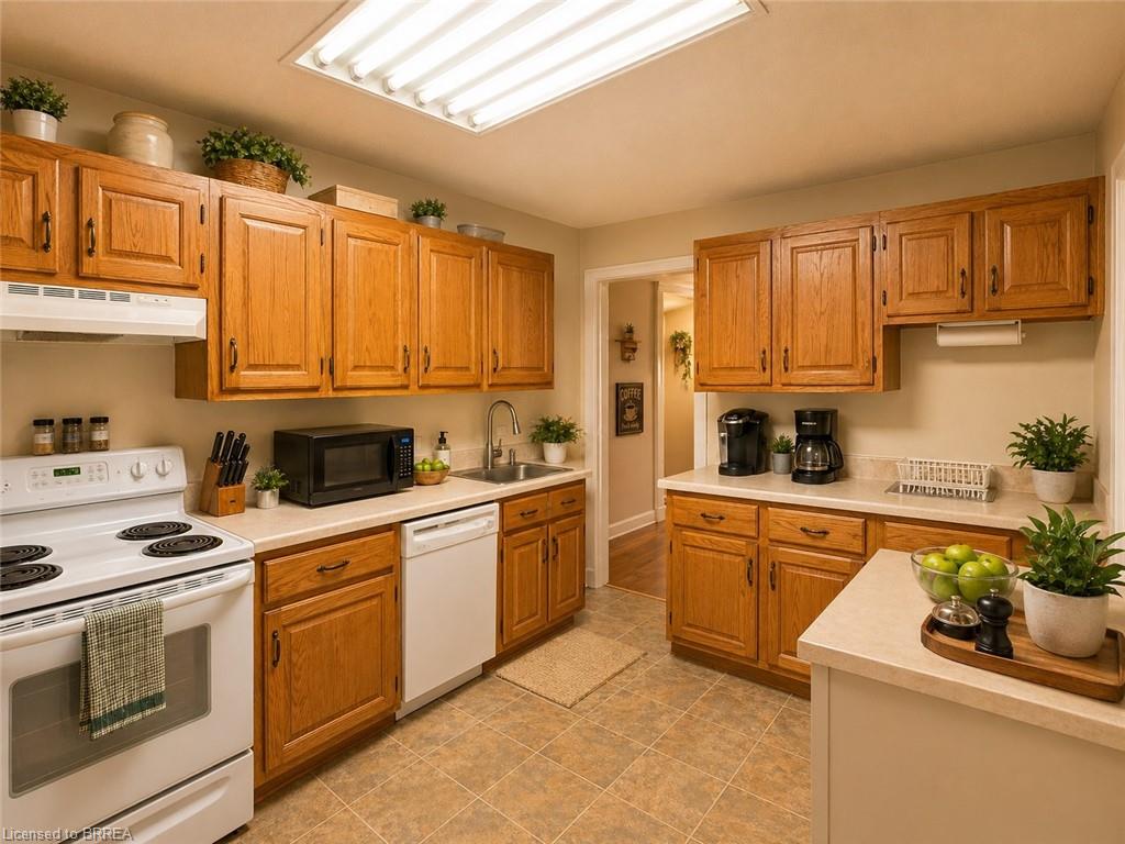 Kitchen featuring wood cabinetry, light-toned countertops, tile flooring, and a full suite of white appliances