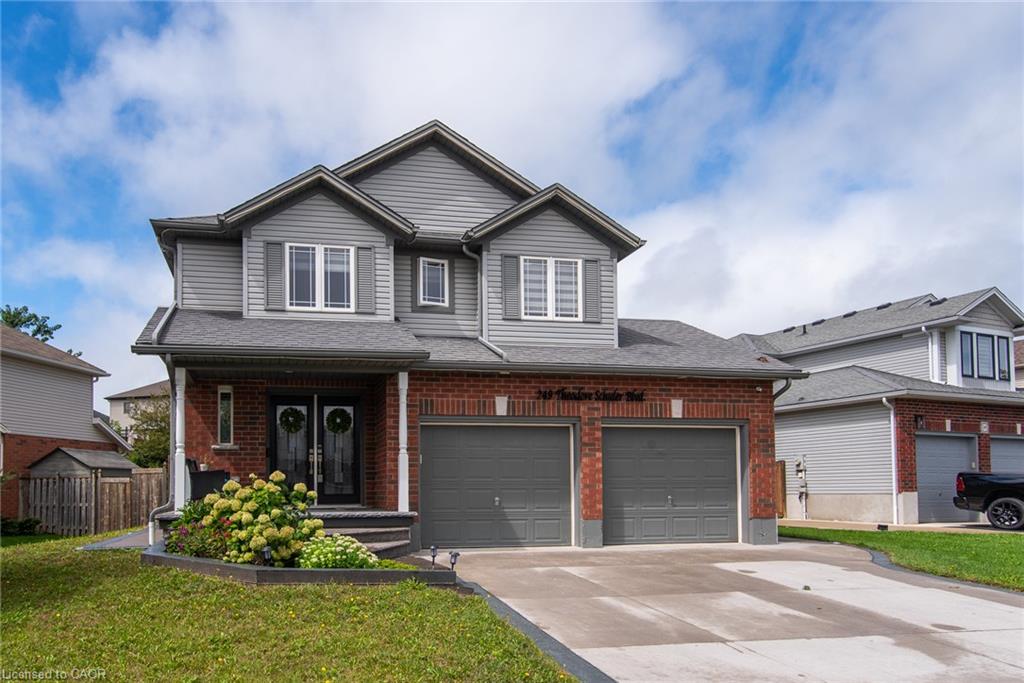 Brick and siding exterior with a covered entry and dual garage doors, featuring a paved driveway and landscaped front yard