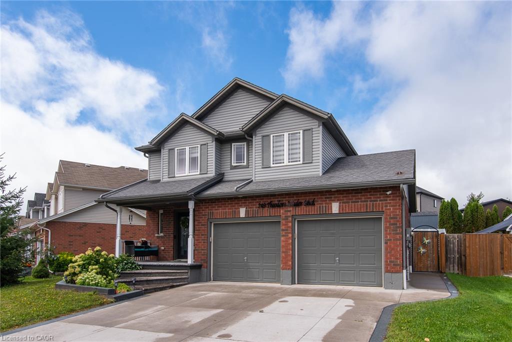 Brick and siding exterior featuring a covered front porch, dual garage doors, and a paved driveway