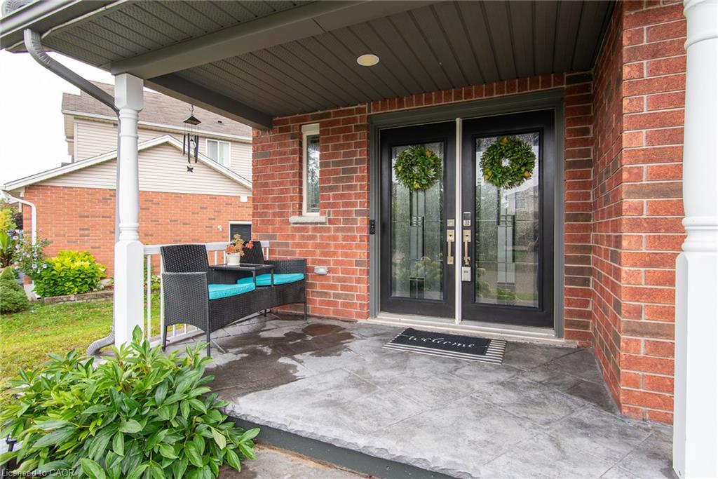 Brick exterior with a covered porch, featuring decorative pillars and a textured concrete surface