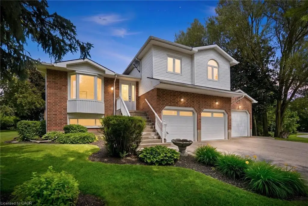 Two-story residence featuring a brick and siding exterior, bay window, three garage bays with white doors, front entry with transom window, and a concrete driveway