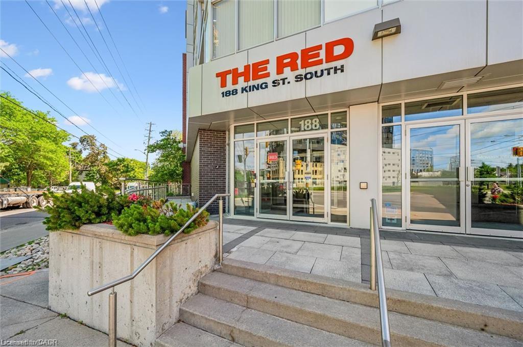 Modern building entrance featuring a glass-front facade, integrated signage, concrete stairs, and stainless steel handrails