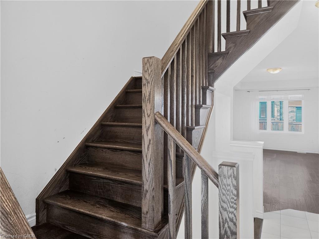 Staircase featuring hardwood stairs with coordinating wood-finish handrails and balusters