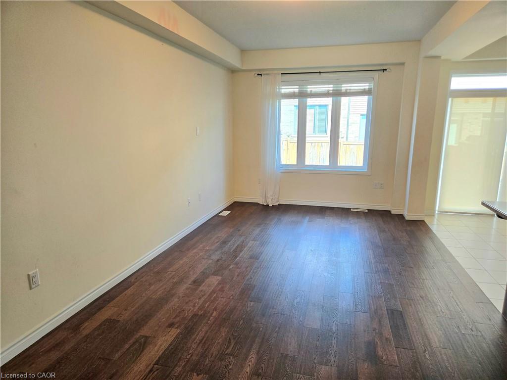 Expansive room featuring wood-finish flooring, a large window, and light-toned walls