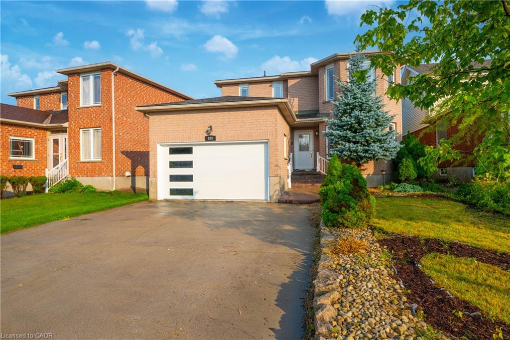 Brick exterior residence featuring a modern garage door with frosted panels, an asphalt driveway, and a stone-lined garden bed
