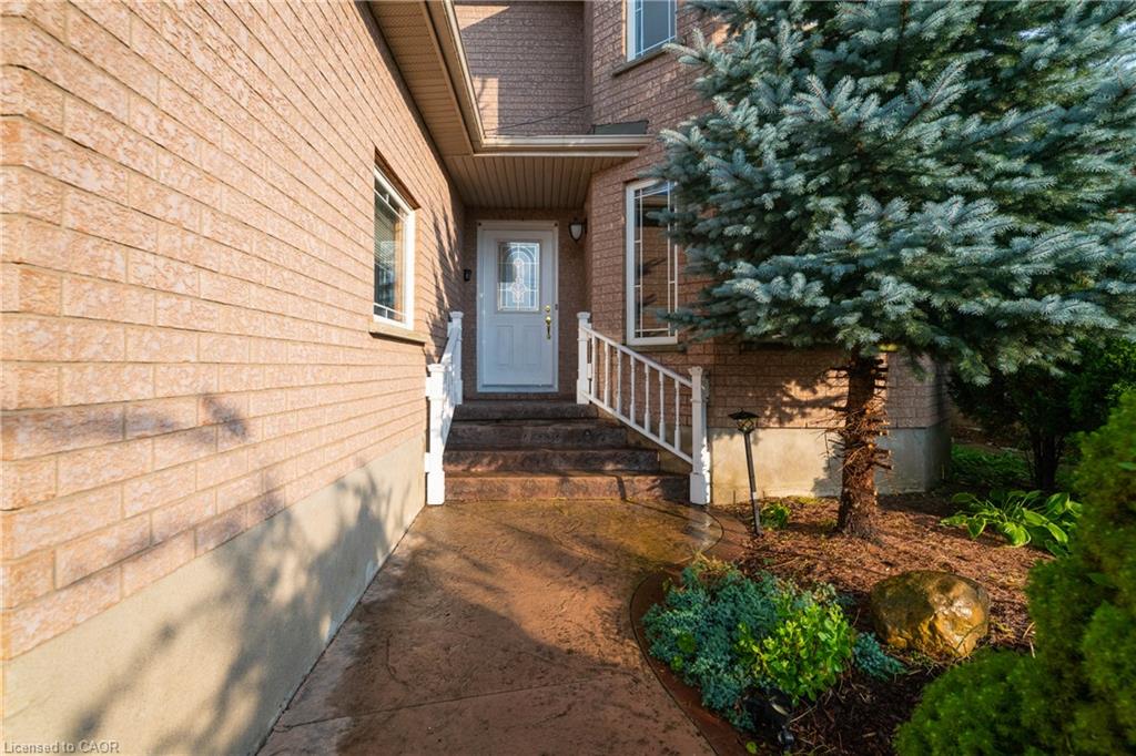 Brick exterior featuring a white entry door with decorative glass, white handrails, and a stained concrete pathway